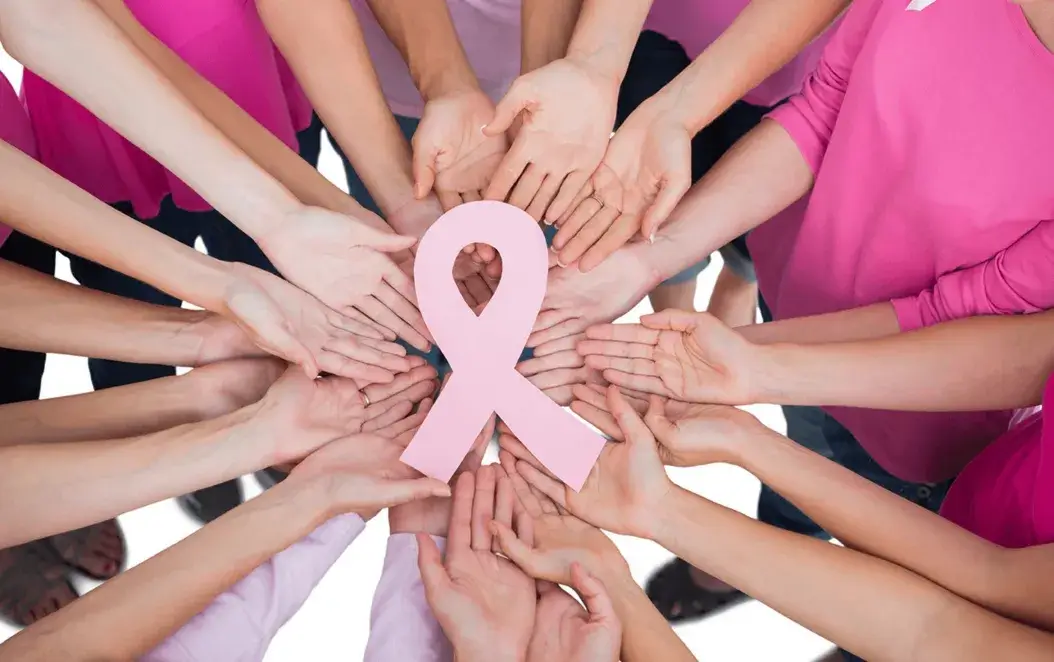 Hands united holding a pink breast cancer awareness ribbon symbol