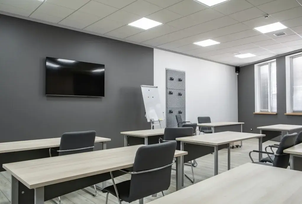 Clean and organized office training room with desks, chairs and wall-mounted TV