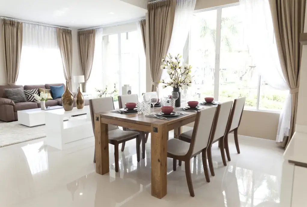 Luxurious dining room connected to living area with large windows and decor