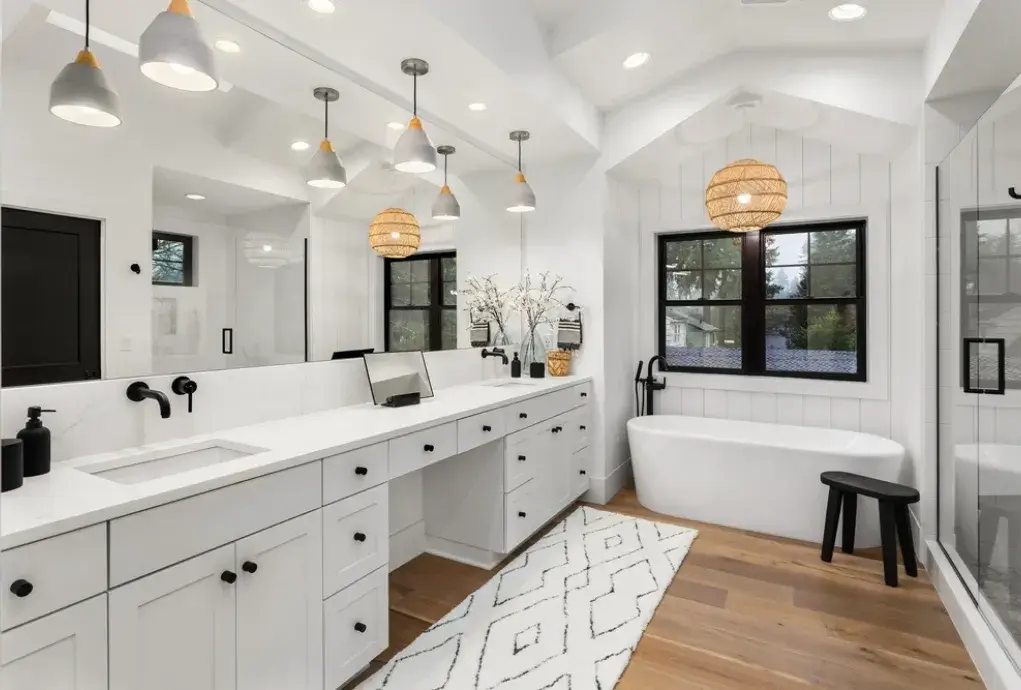 Bright bathroom with double vanity, soaking tub and natural wood flooring