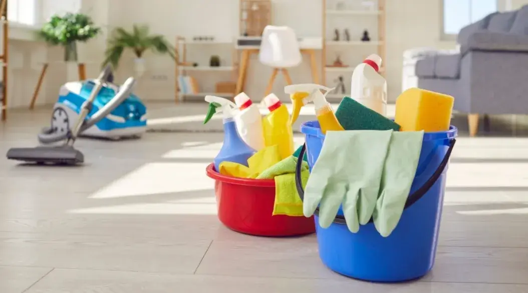 Buckets with cleaning products and gloves in a bright, clean living room